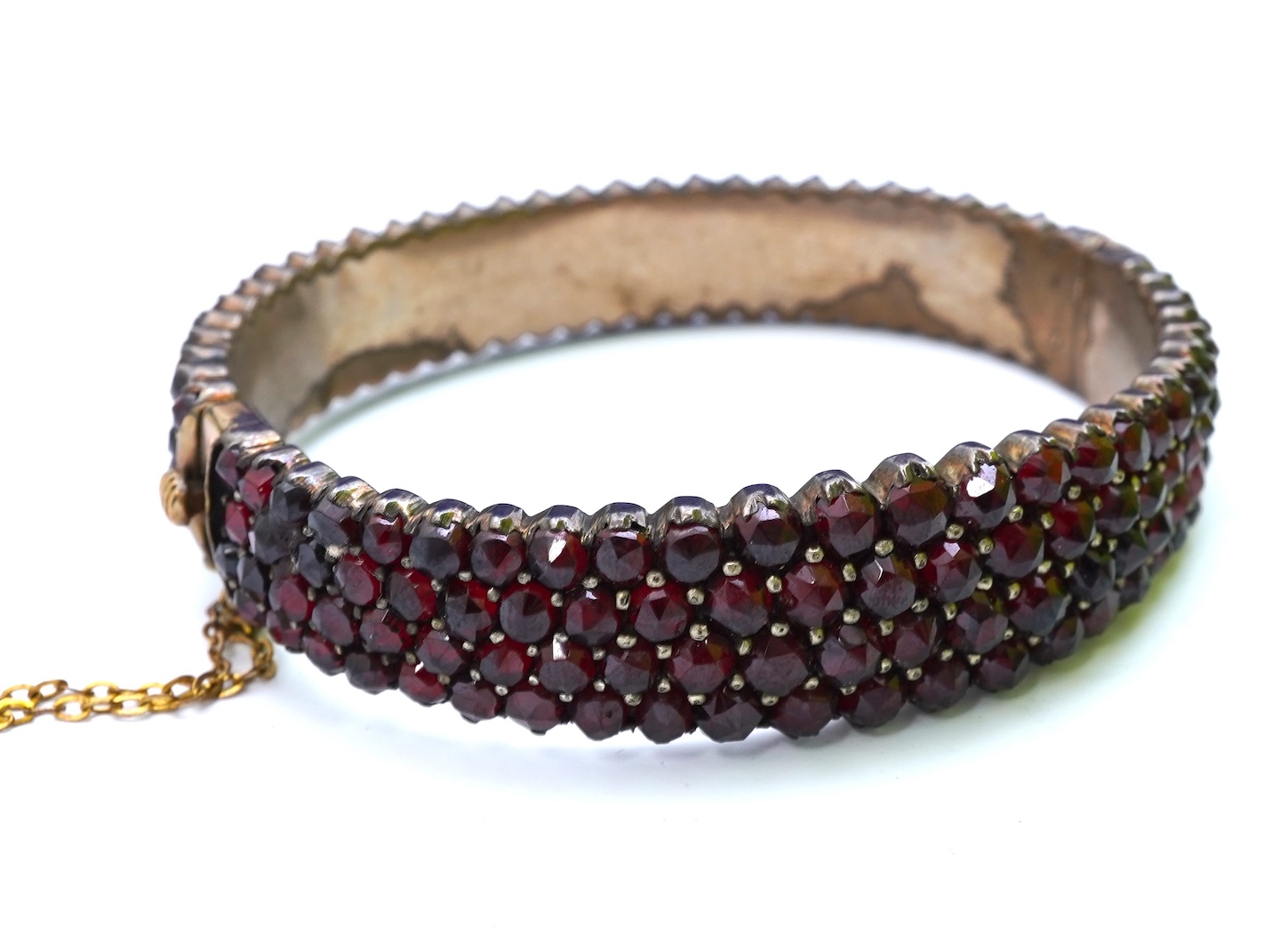 A suite of garnet and paste jewellery, comprising: a brooch, 5cm diameter; a bangle, inner circumference 16cm; two rings, sizes I and M; a pair of earrings, and a single earring, each set with rose-cut garnets; and a pai